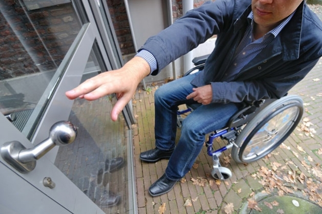 Photo d'une personne en fauteuil roulant essayant d'ouvrir une porte